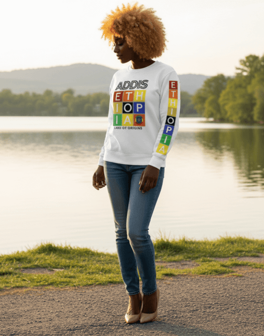 Woman wearing a white Addis, Ethiopia, color block, long-sleeve sweat shirt standing by a lake.