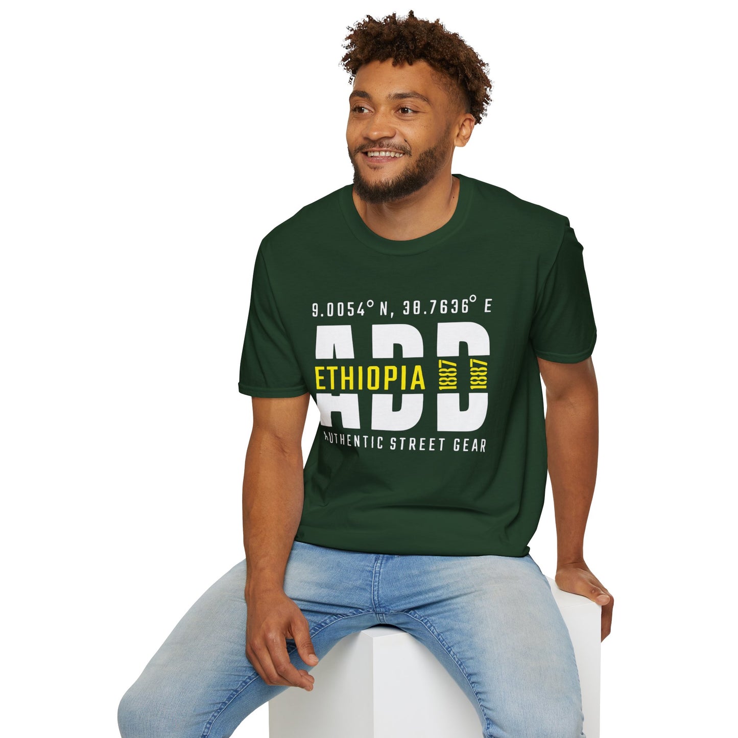 Man wearing a green t-shirt with Addis Ababa, Ethiopia, ADD Airport code and coordinates, sitting on a white stool against a white background.