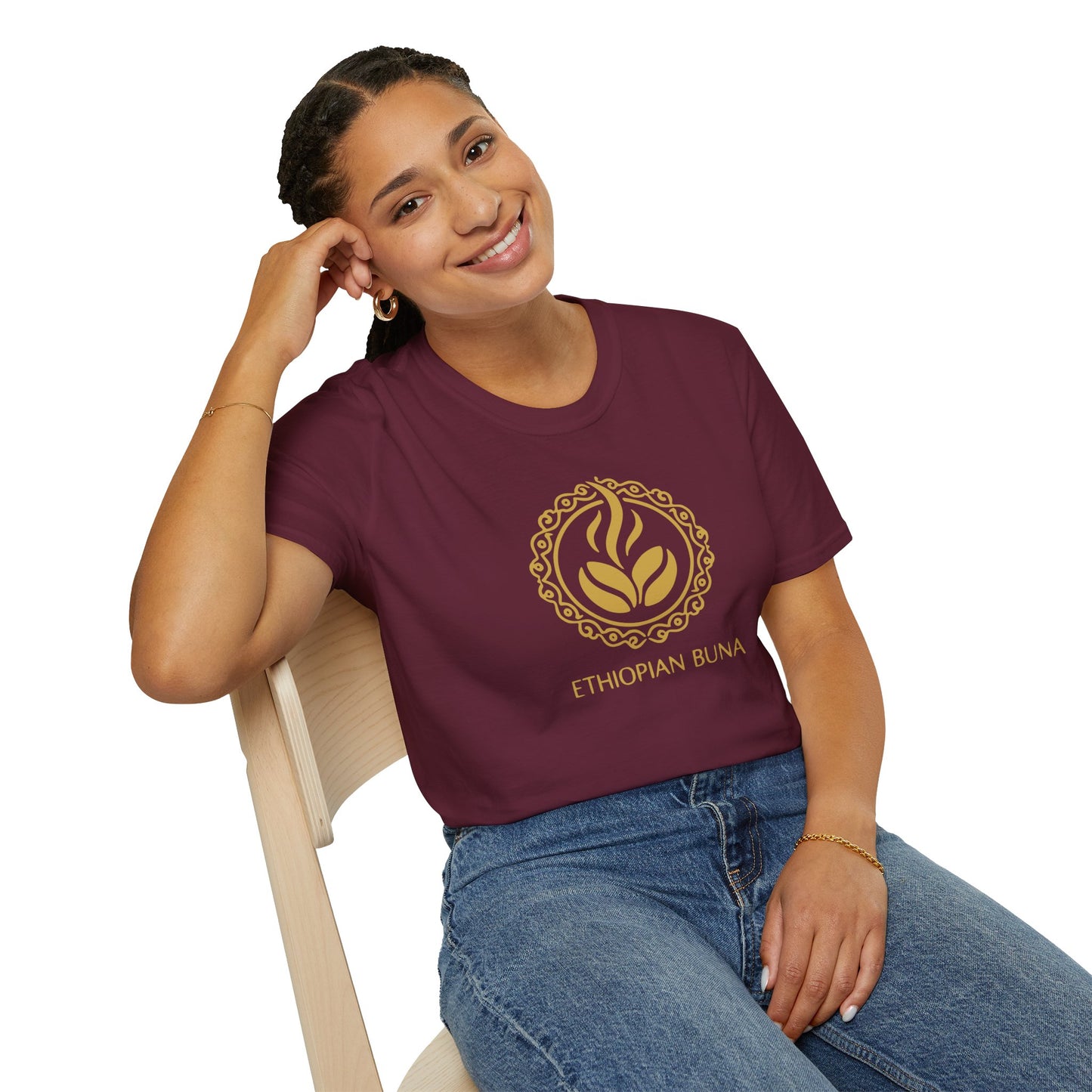 A woman wearing a maroon Ethiopian Buna graphic print t-shirt sitting in a chair