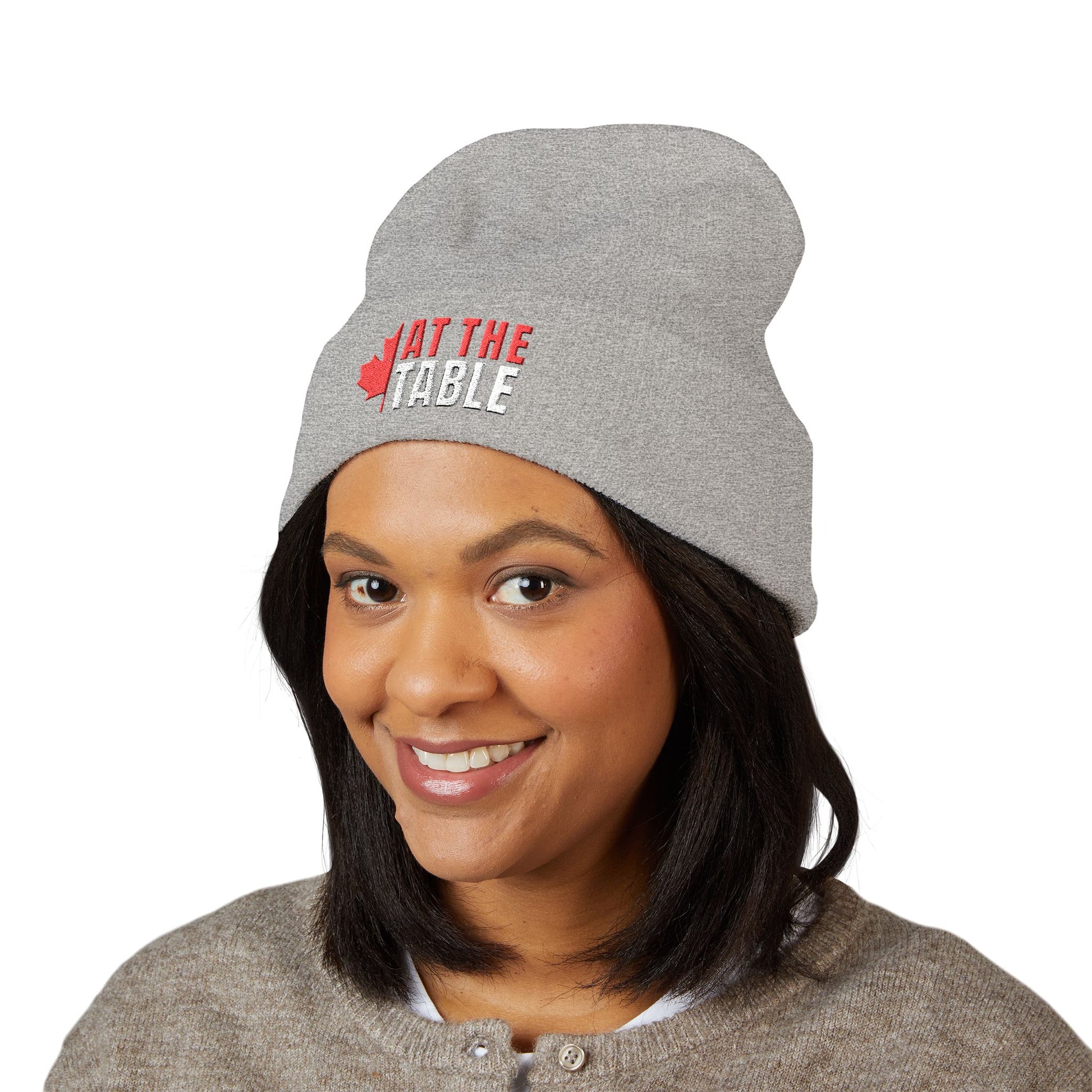 Person wearing a gray beanie with 'Sit at the Table' text on a white background
