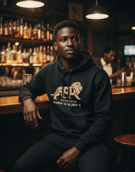Man wearing a black hoodie with a lion logo and Addis Ababa, Ethiopia coordinates sitting at a bar.