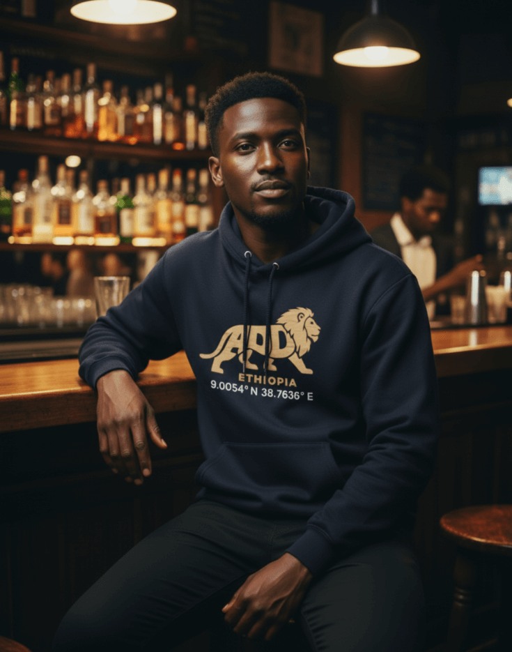Man wearing a navy blue hoodie with a lion logo and Addis Ababa, Ethiopia coordinates sitting at a bar.