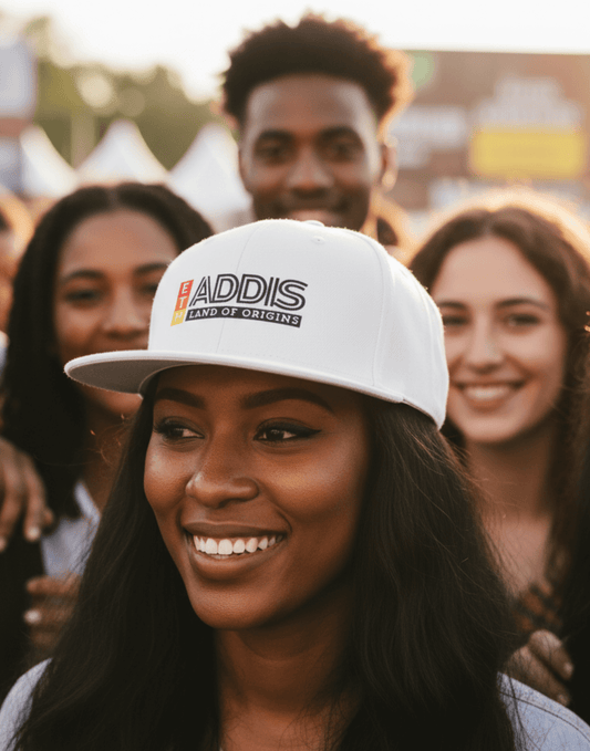 Woman wearing a white snapback cap with 'ADDIS Land of origins' text with friends at a concert