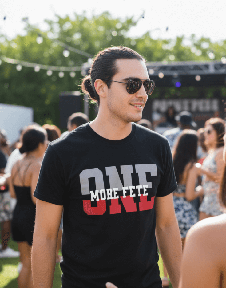 Man wearing sunglasses and a black t-shirt with 'ONE MORE FETE' text at an outdoor event.