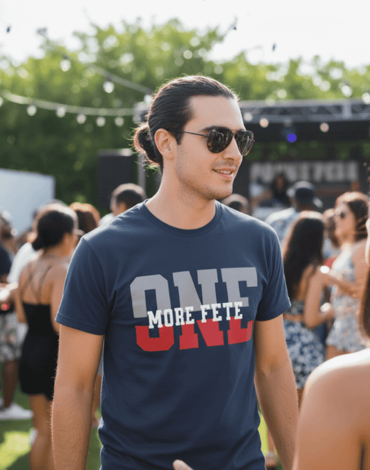Man wearing sunglasses and a navy blue t-shirt with 'ONE MORE FETE' text at an outdoor event.