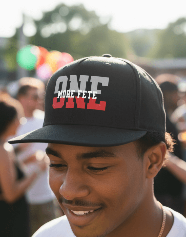 Person wearing a black cap with 'ONE MORE FETE' text, blurred background of people and colorful lights