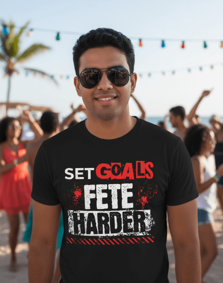 Man wearing a black t-shirt with text, Set Goals Fete Harder, at a party with people in the background