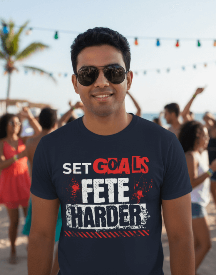 Man wearing a navy blue t-shirt with text, Set Goals Fete Harder, at a party with people in the background