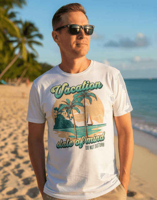 Man standing on the beach wearing a white t-shirt with a graphic print and text that says Vacation - State of Mind - Do not disturb