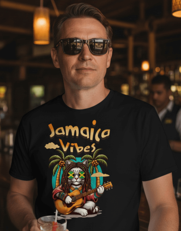 Man standing in a bar wearing a black t-shirt with Jamaica Vibes text and Jamaica flag reggae inspired graphic. 