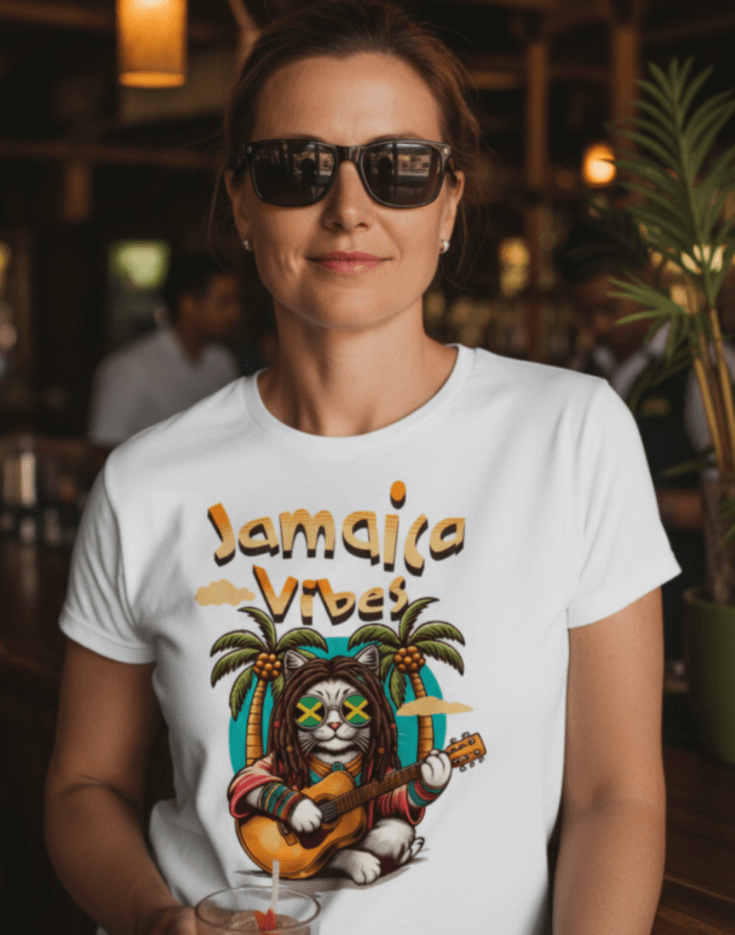 Woman standing in a bar wearing a white t-shirt with Jamaica Vibes text and Jamaica flag reggae inspired graphic. 