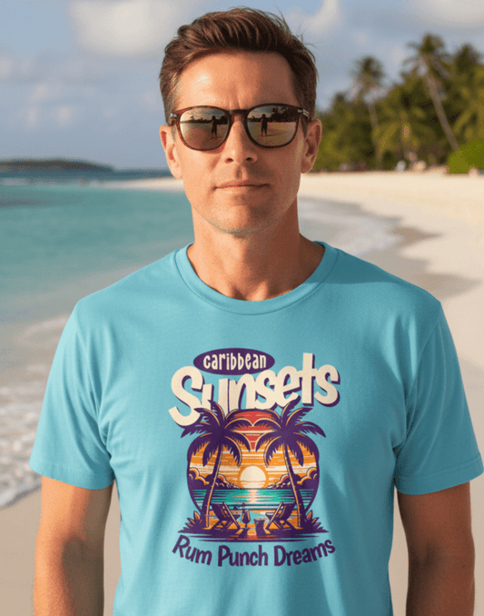 Man on the beach wearing a sky blue t-shirt that says Caribbean Sunsets, Rum Punch Dreams with a beach sunset graphic.