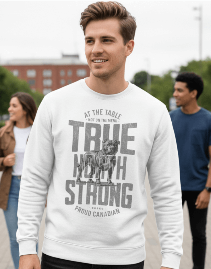 Man wearing a white sweatshirt with text and graphics, True North Strong, standing outdoors with people in the background.