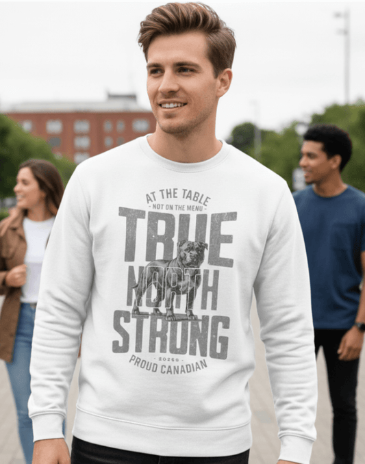 Man wearing a white sweatshirt with text and graphics, True North Strong, standing outdoors with people in the background.