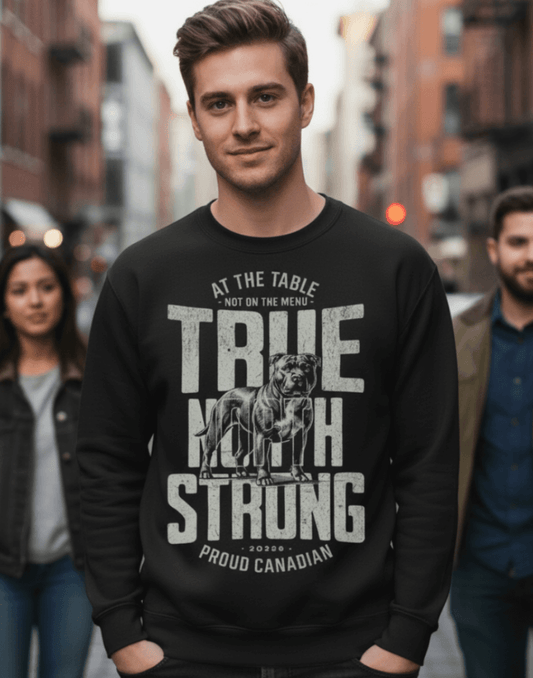 Man wearing a black sweatshirt with text and graphics, True North Strong, standing outdoors with people in the background.