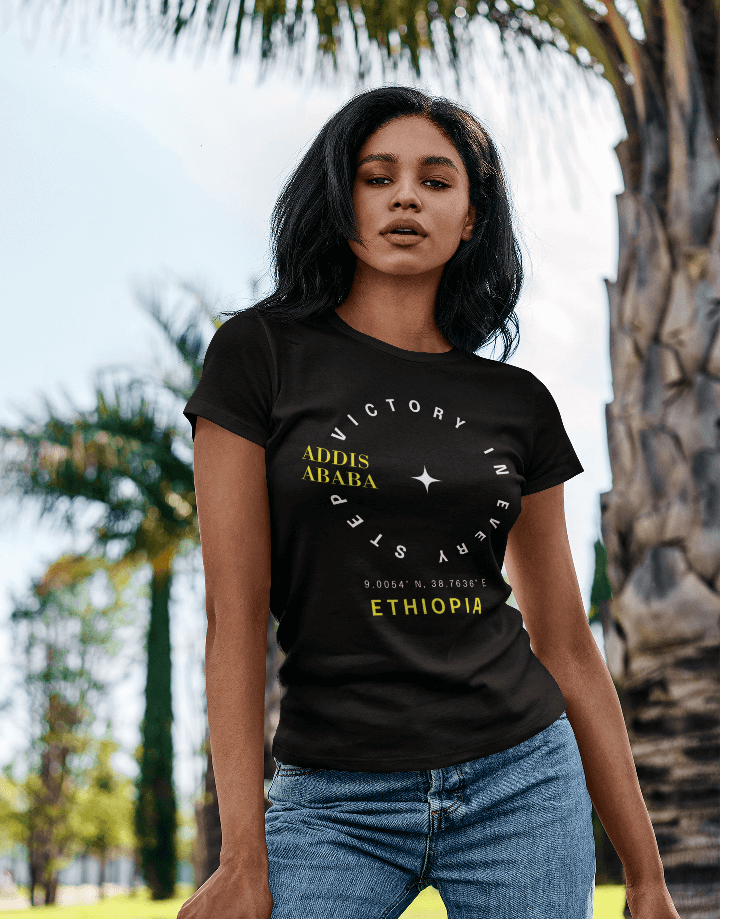 Woman wearing a black Ethiopian Addis Ababa t-shirt with minimalist text, standing outdoors with trees in the background