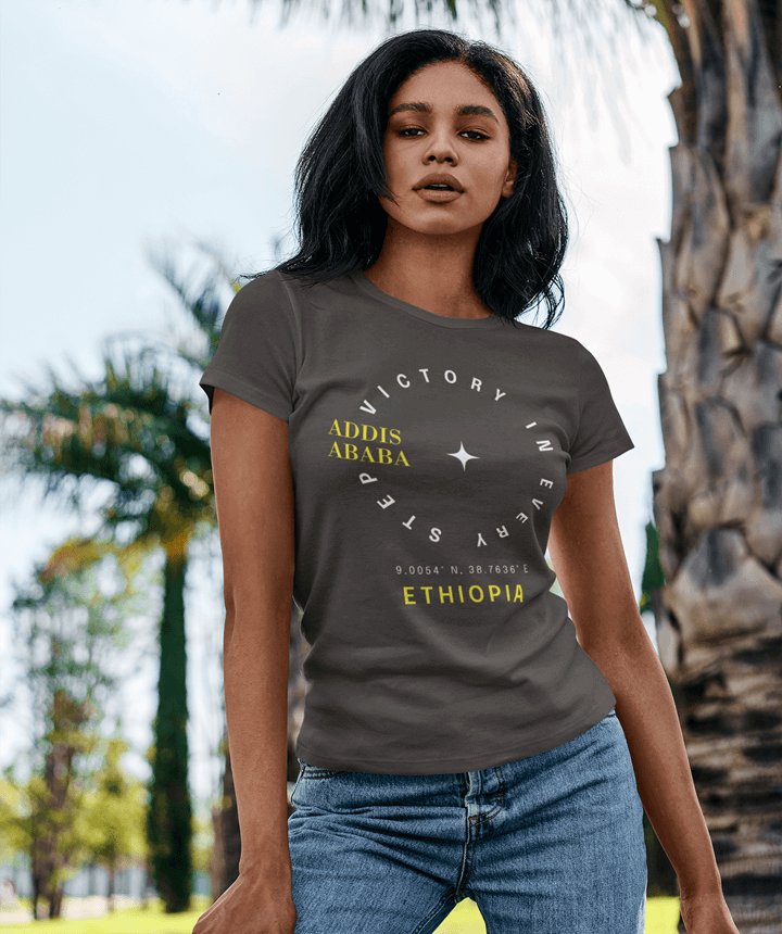 Woman wearing a gray t-shirt with 'Addis Ababa, Ethiopia' text outdoors.