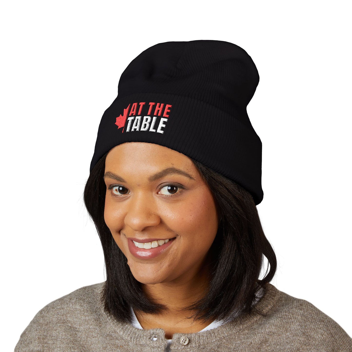 Person wearing a black beanie with 'At the Table' logo on a white background
