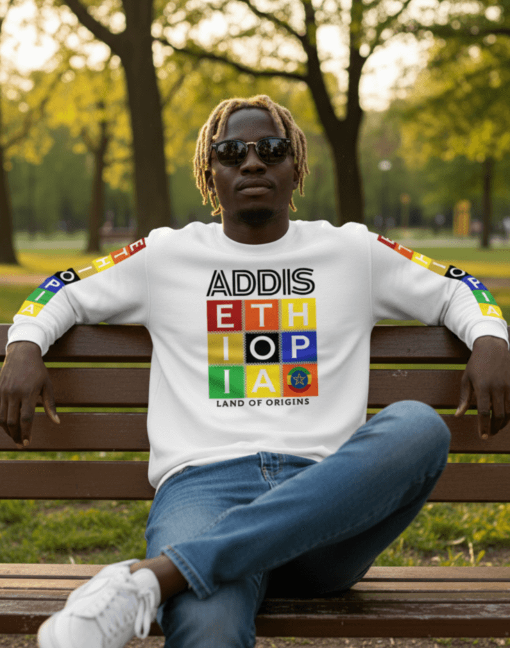 Man wearing a white Addis, Ethiopia, color block,  long-sleeve sweat shirt sitting on a bench