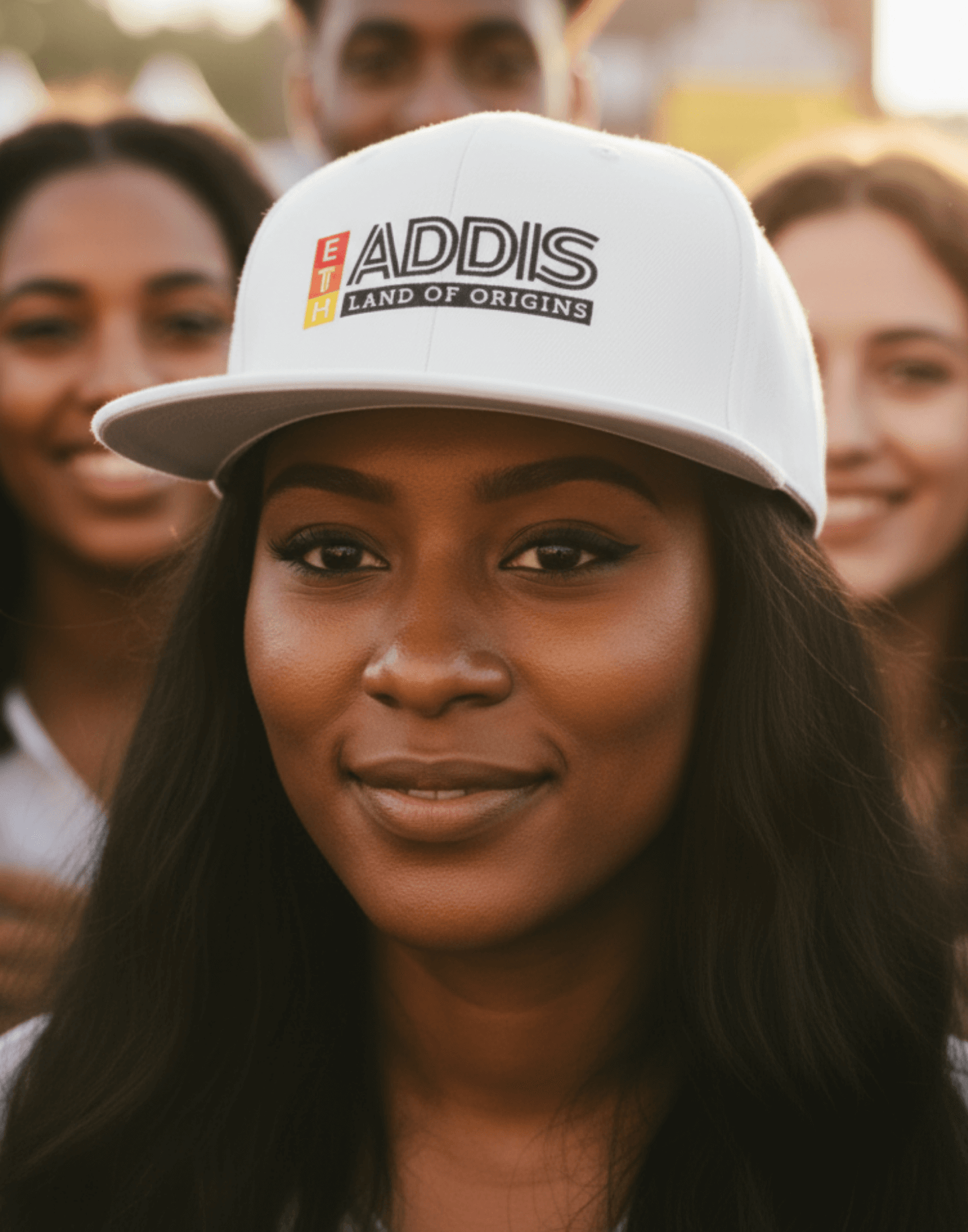 Woman wearing a white snapback cap with 'ADDIS Land of origins' text with friends at a concert
