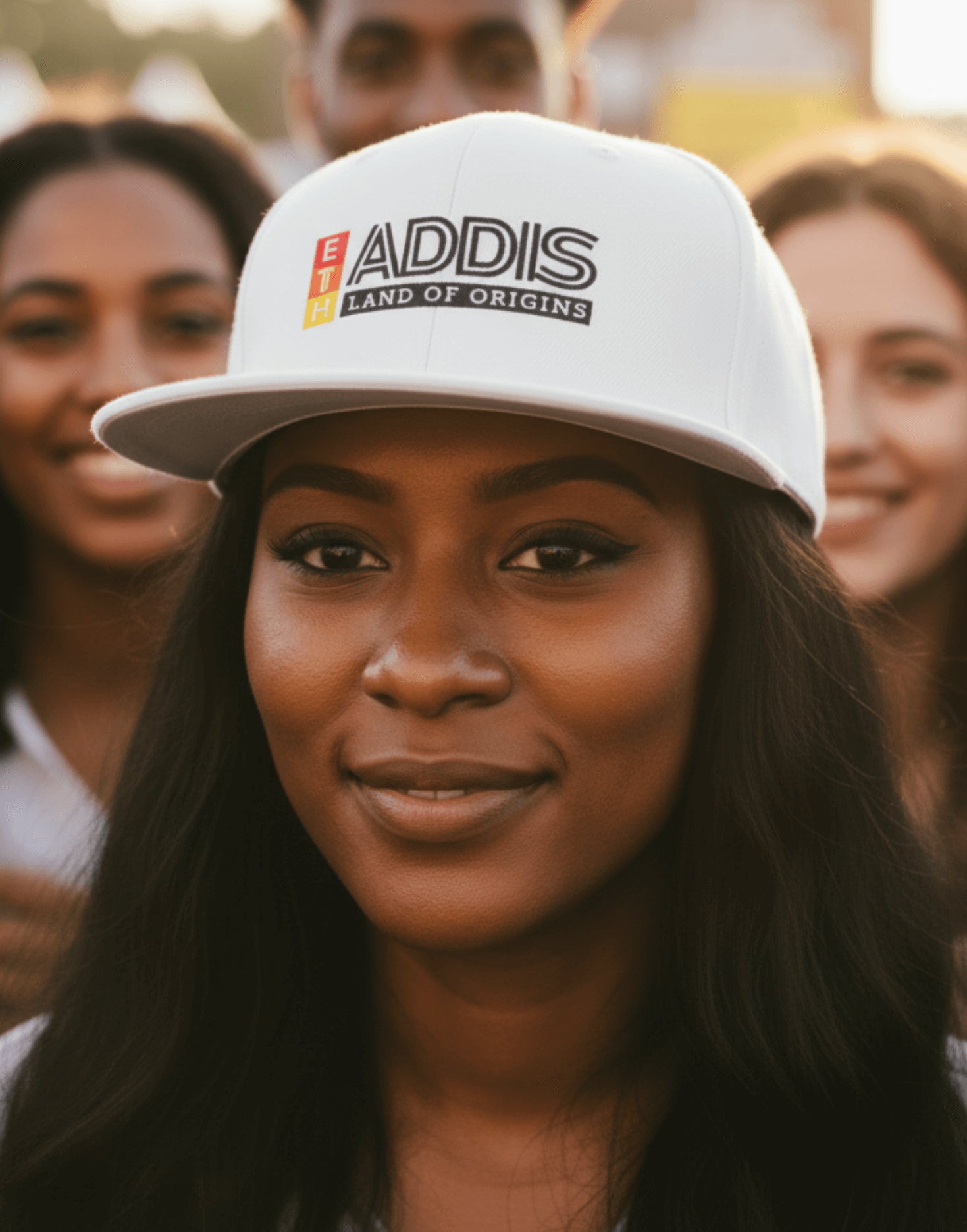 Woman wearing a white snapback cap with 'ADDIS Land of origins' text with friends at a concert
